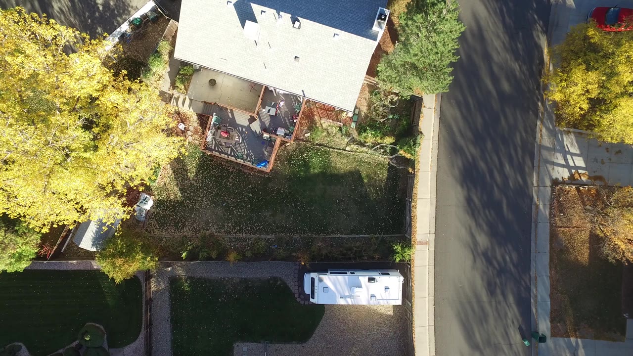Overhead residential yard with roof, street, trees, and parked RV.