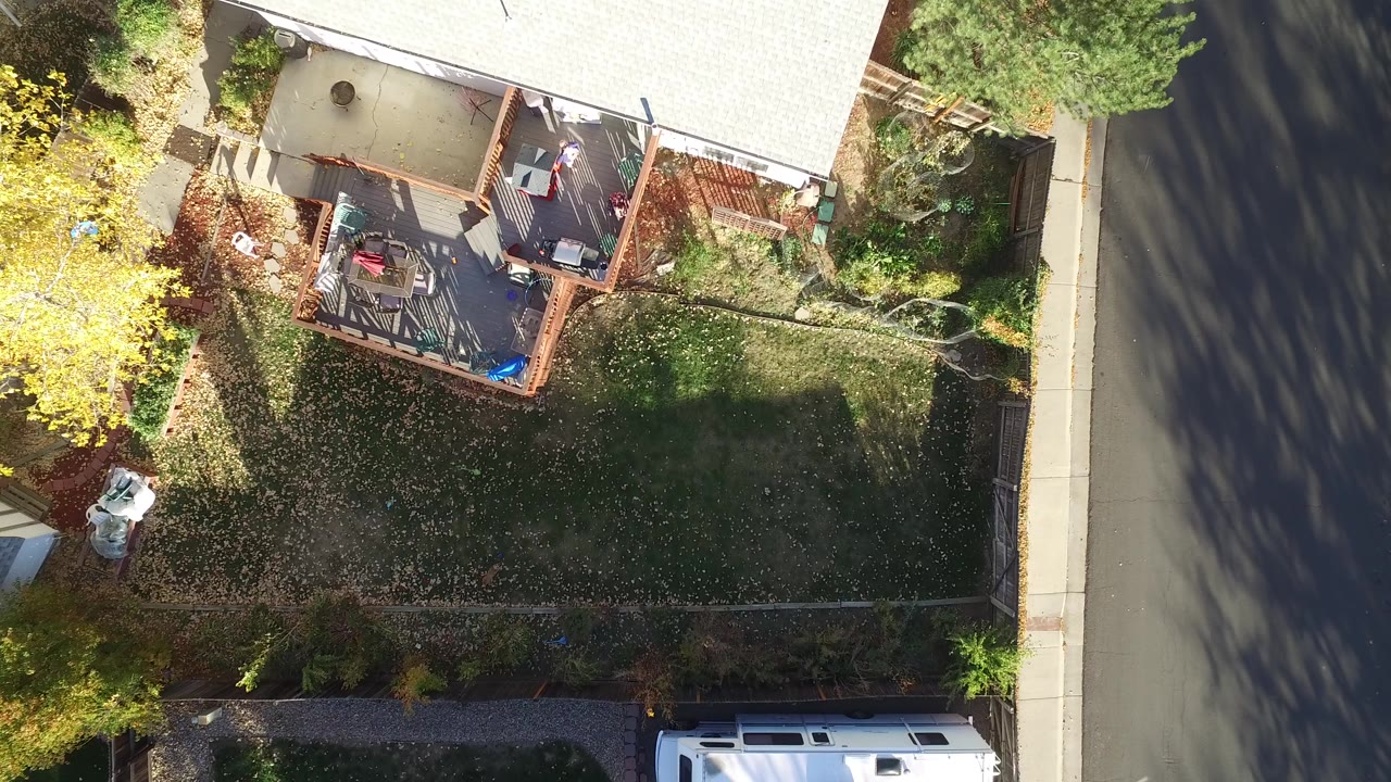 Overhead view of a fenced backyard beside a street.
