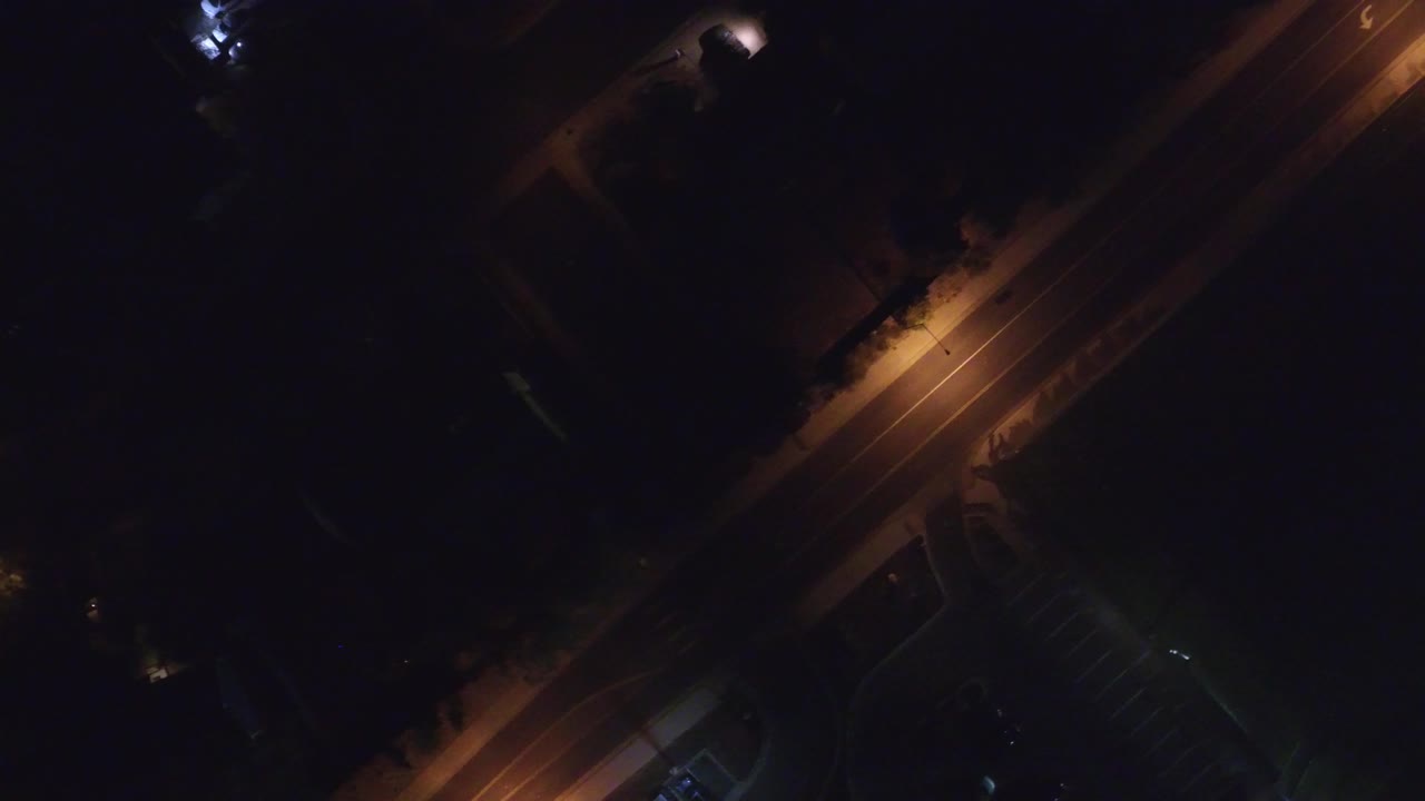 Dark overhead road scene with streetlights and lane markings