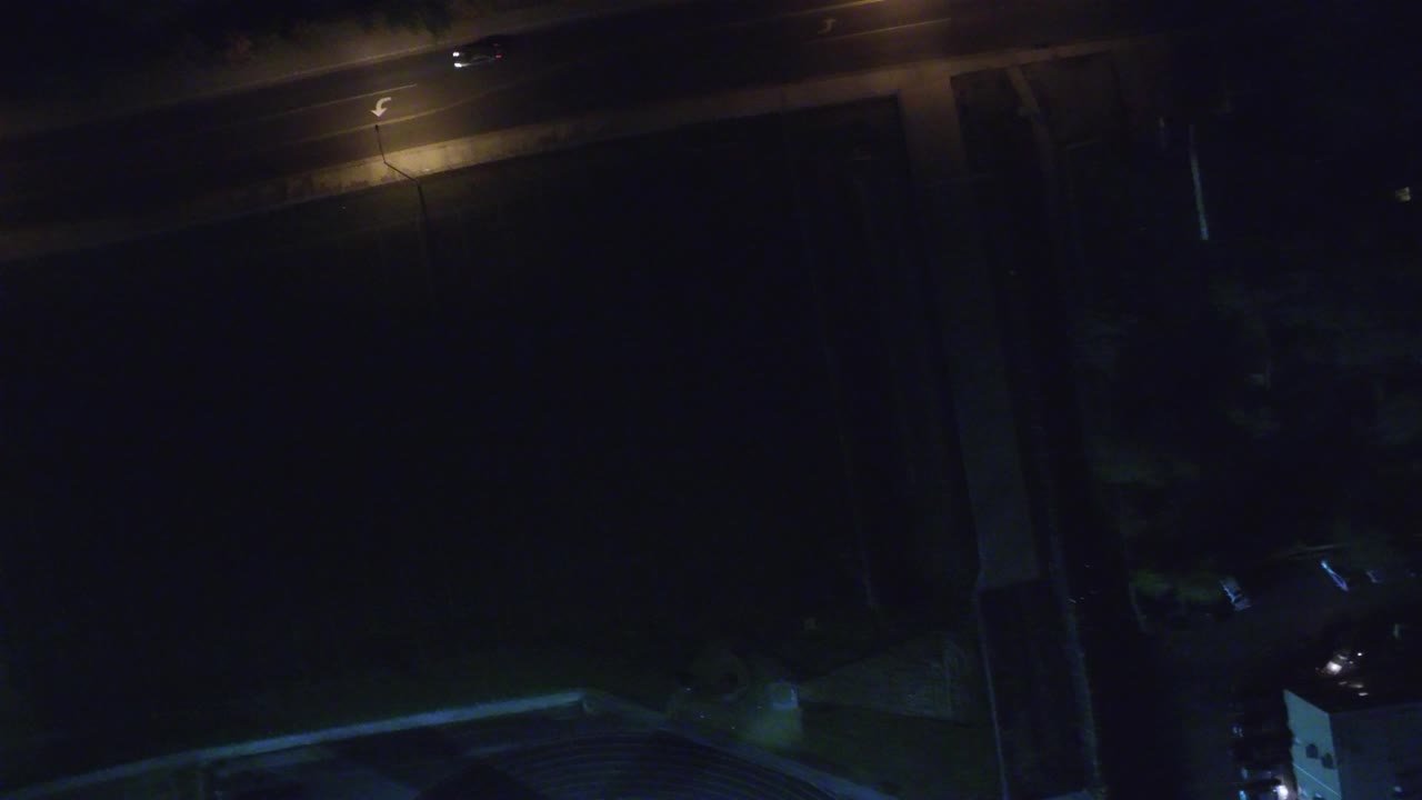 Dark aerial view of a road with a glowing street lamp