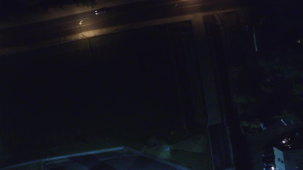 A similar elevated Hidden Lake, Colorado frame shows the street lamp along the upper road, a broad dark area in the middle, and faint rooftops at the lower edge with no visible people.