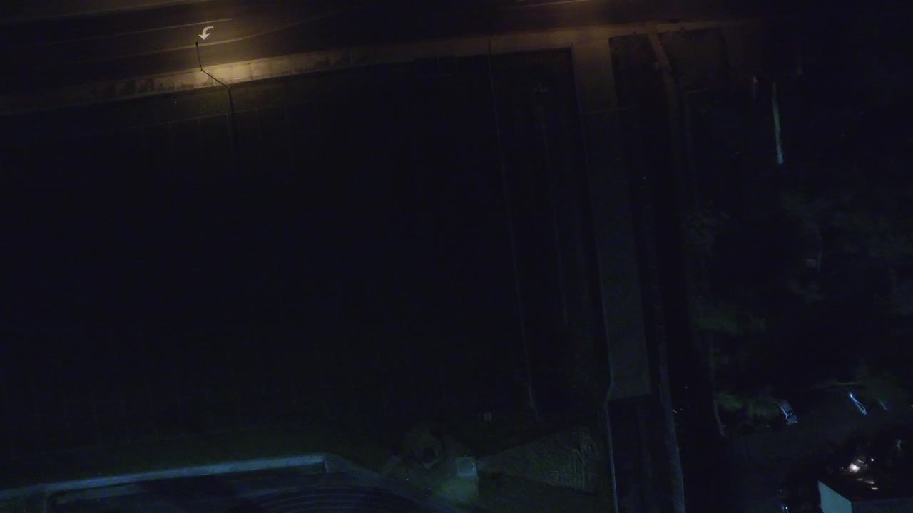 Very dark overhead yard and road at night under a streetlight.