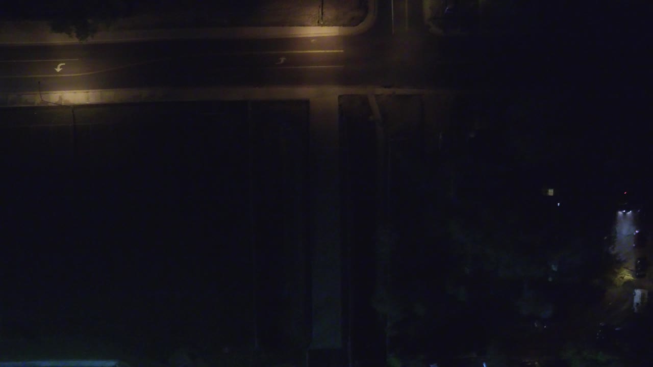 Dark overhead street intersection with streetlights and rooftops