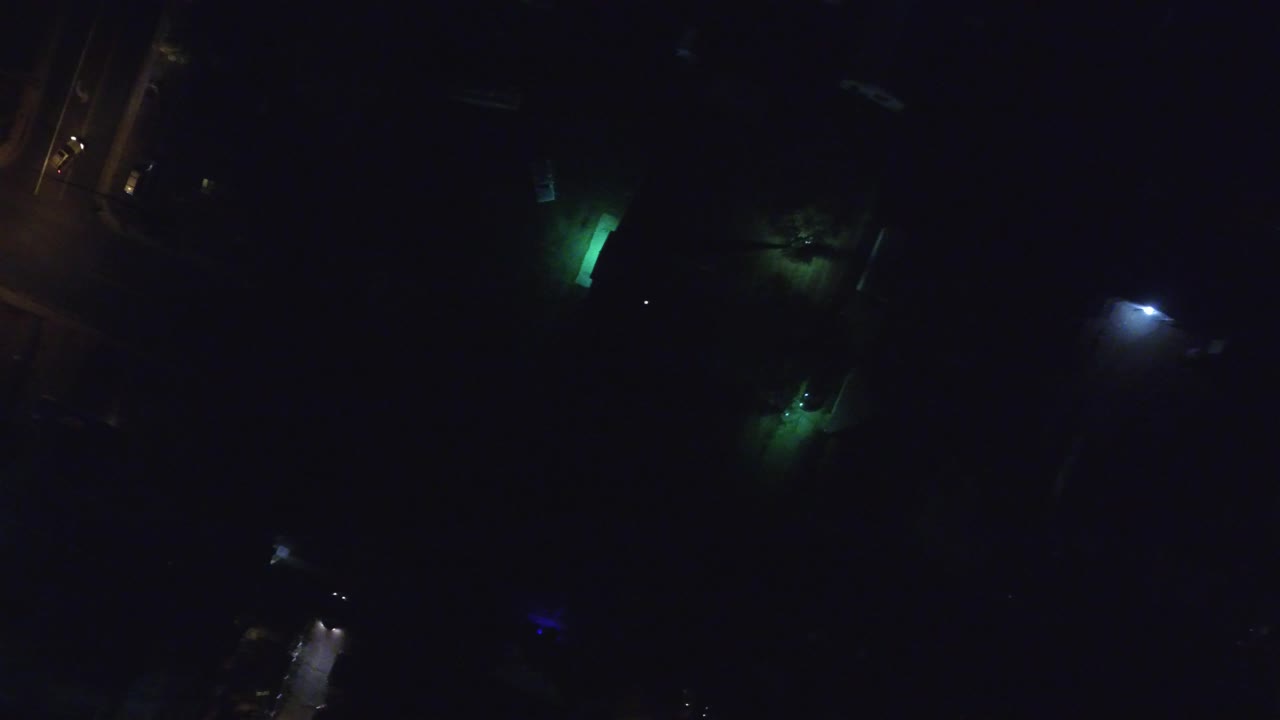 Dark aerial-like frame with green glow and small white light