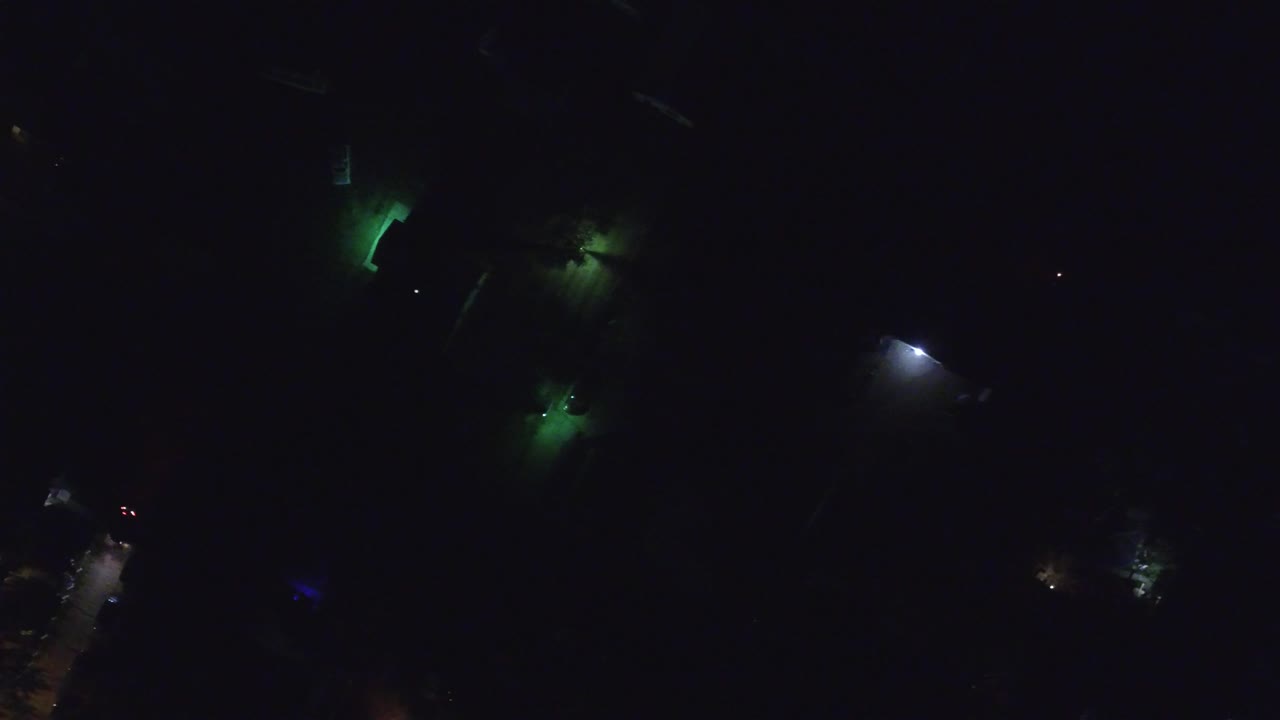 Dark aerial night view with scattered green and white lights