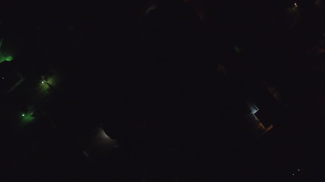 Dark aerial neighborhood view with scattered green and white lights