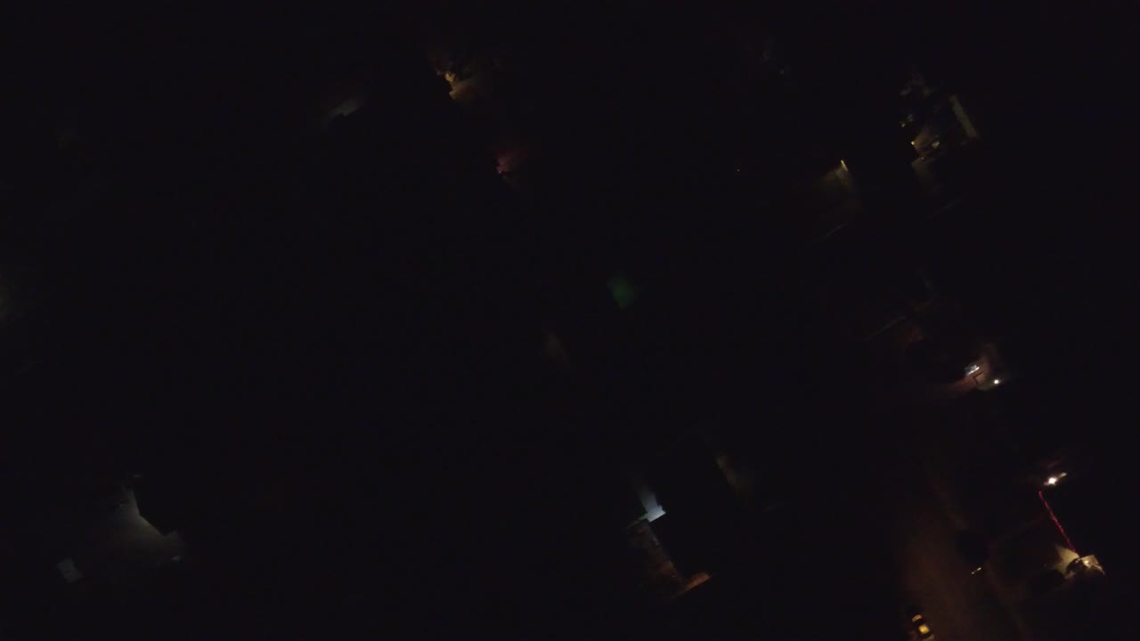 Very dark overhead view in Hidden Lake, Colorado with scattered warm lights and faint roof or road shapes, no visible people.