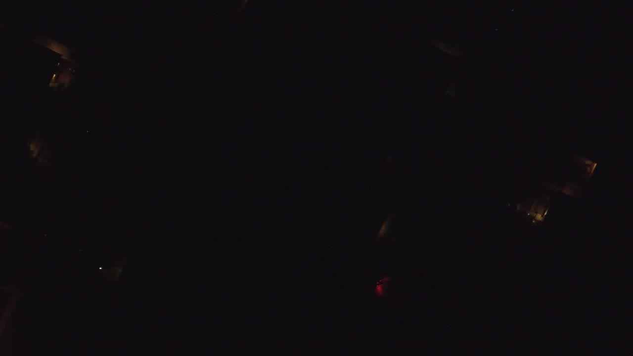 Nearly black Hidden Lake, Colorado night aerial frame with faint amber lights near the upper and lower areas, no visible people.