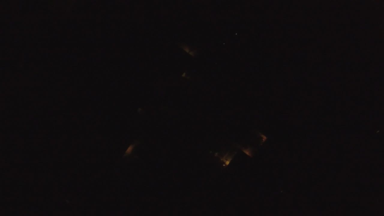 Very dark city-at-night frame with scattered tiny lights.