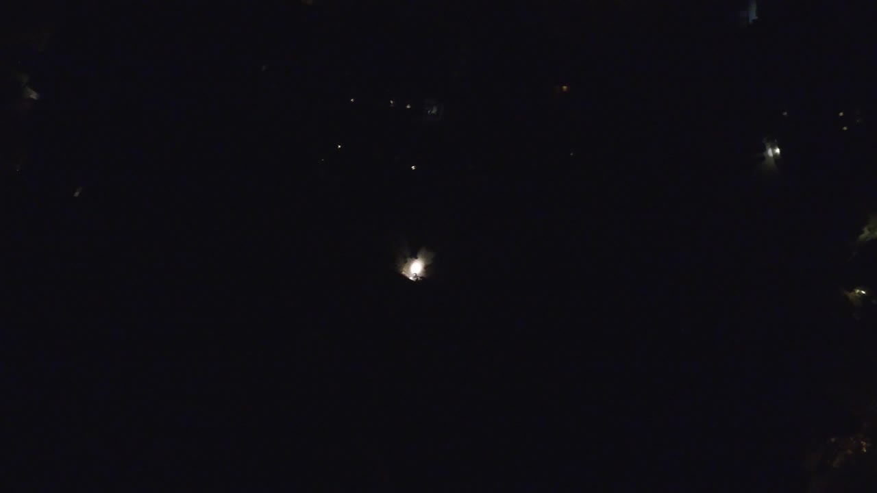 Very dark aerial night view with scattered small lights.