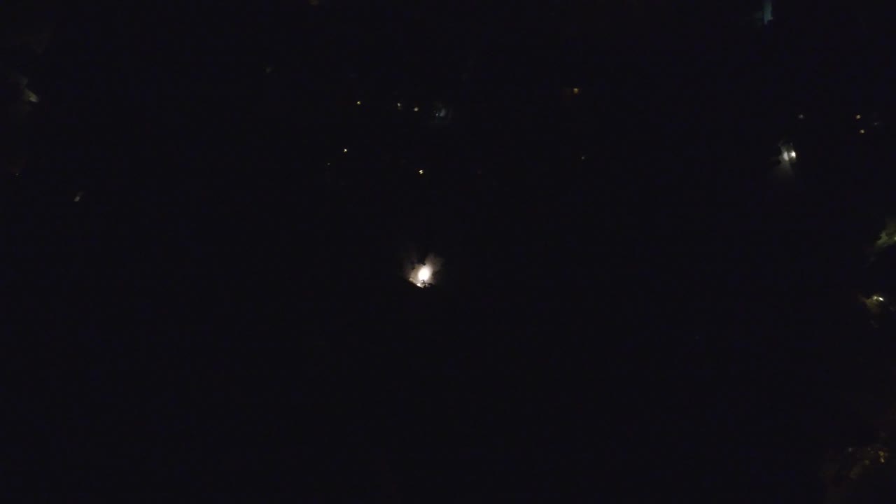 Second frame of the Hidden Lake, Colorado night aerial, with isolated bright points against deep shadow and no visible people.