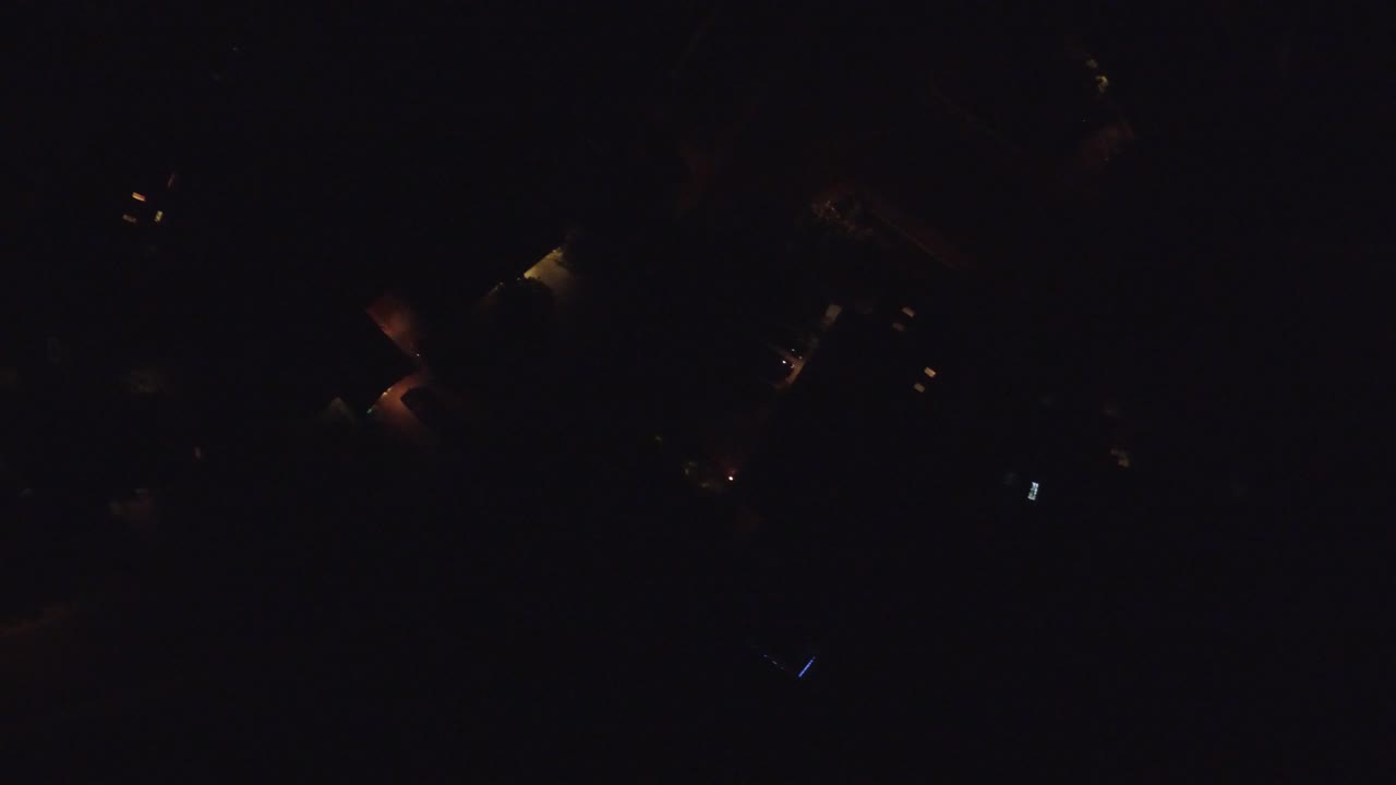Mostly black frame with a few distant orange lights.