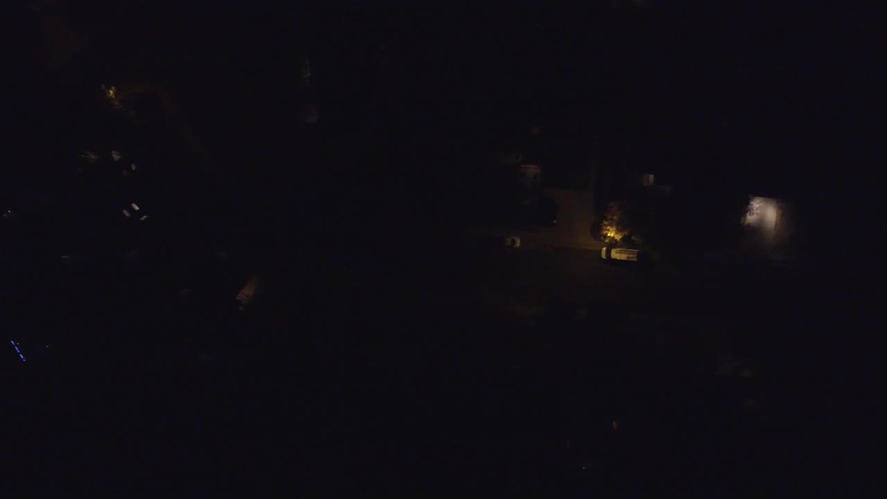 High night aerial over Hidden Lake, Colorado showing faint road lines and isolated warm light sources around private homes, no visible people.