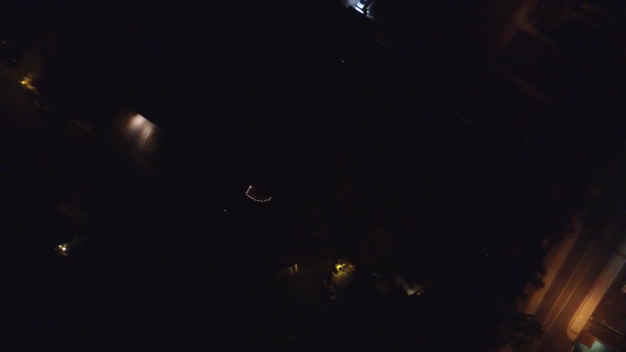 Dark overhead street view with warm lamps and road edges.