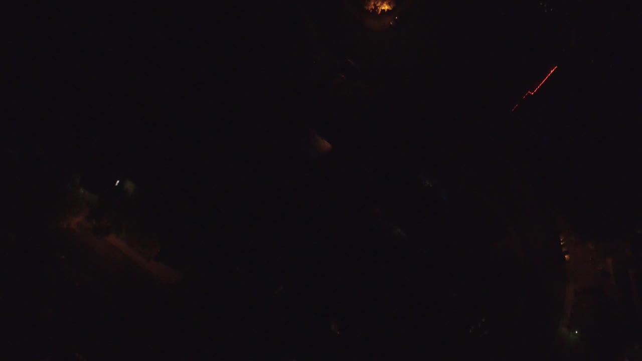 A very dark aerial frame over Hidden Lake, Colorado, with a few orange street lamps and faint road shapes visible, no visible people.