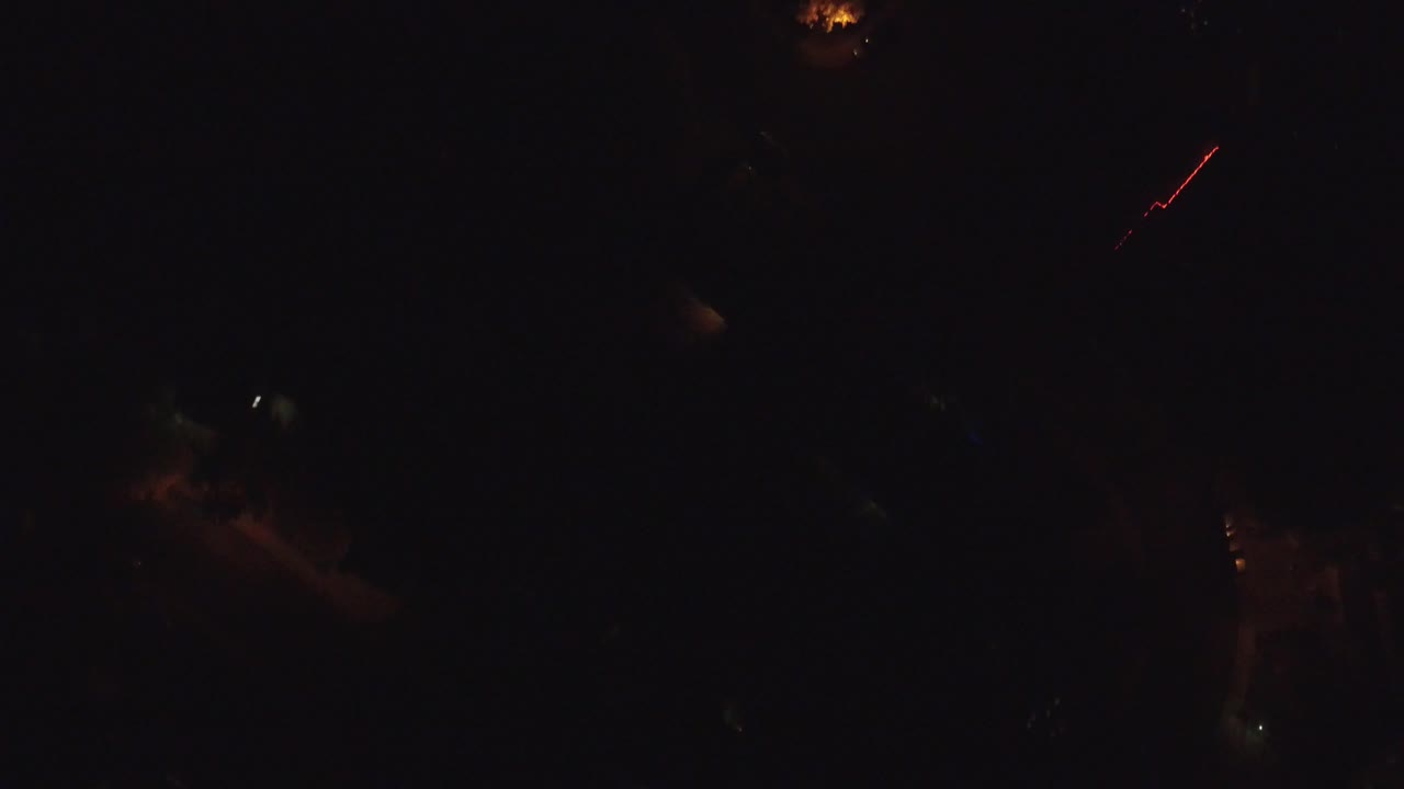 A night aerial view in Hidden Lake, Colorado, with one bright orange lamp near the upper edge and dim residential shapes below, no visible people.