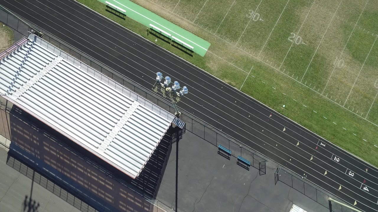 Overhead view of white stadium bleachers beside a black running track.
