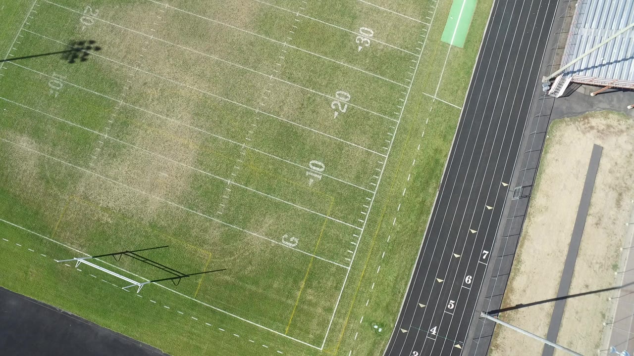 Overhead view of grass field, track, sand pit, and goal frame.