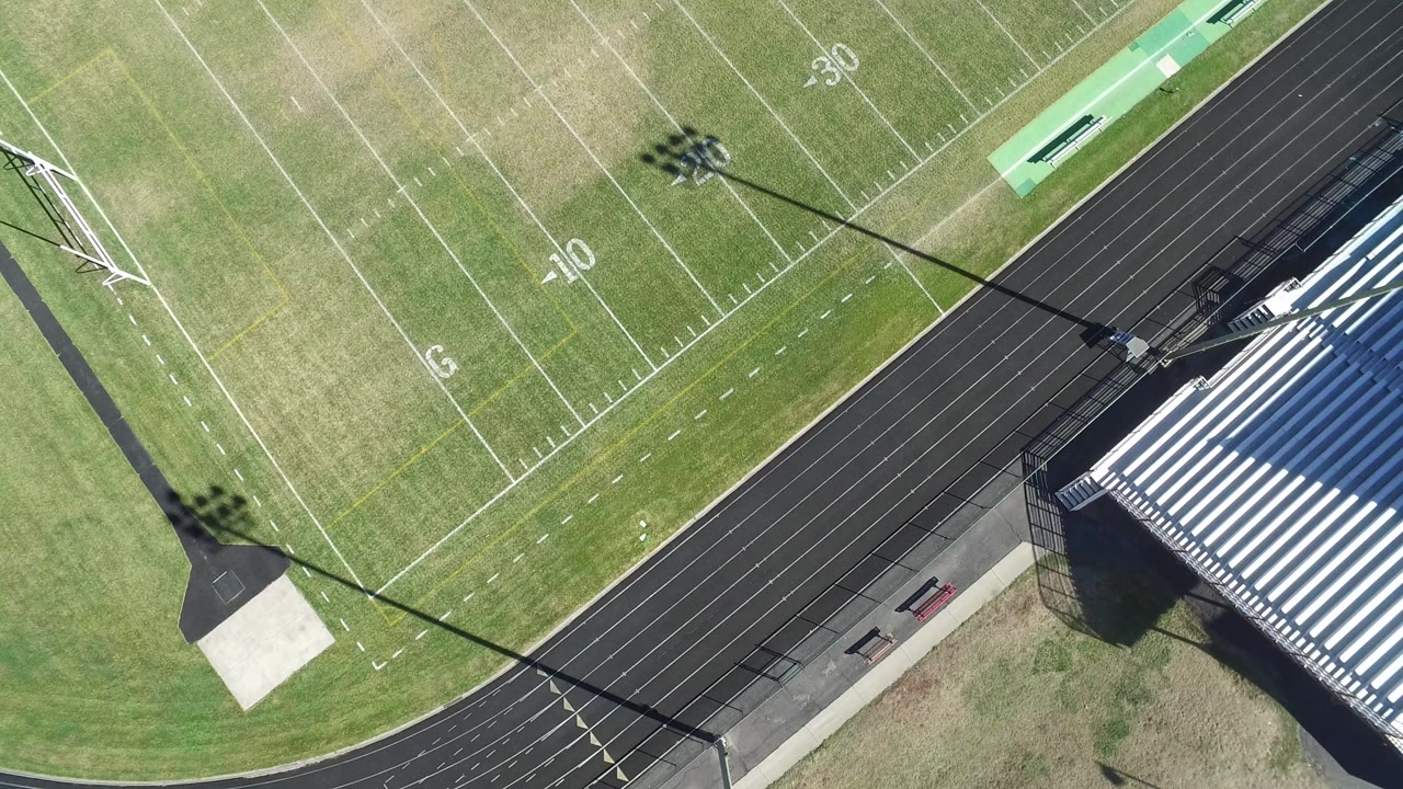 Overhead view of a football field beside a running track and bleachers.