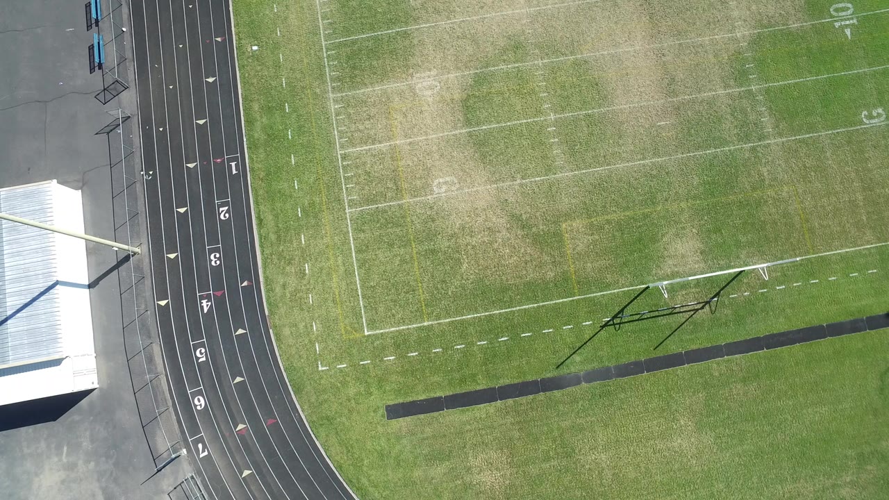 Overhead view of a running track beside a marked grass field.