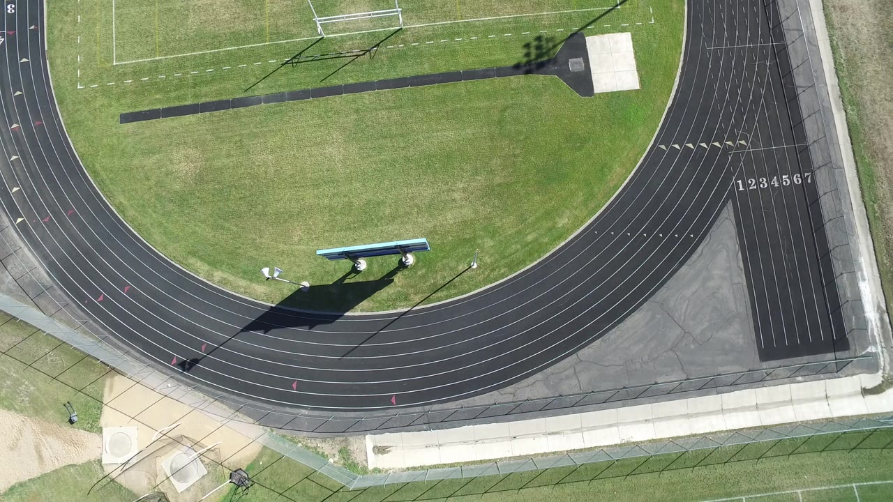 High aerial view in Hidden Lake, Colorado with the track curve centered lower in frame, lane numbers at right, grass infield above, and no visible people.