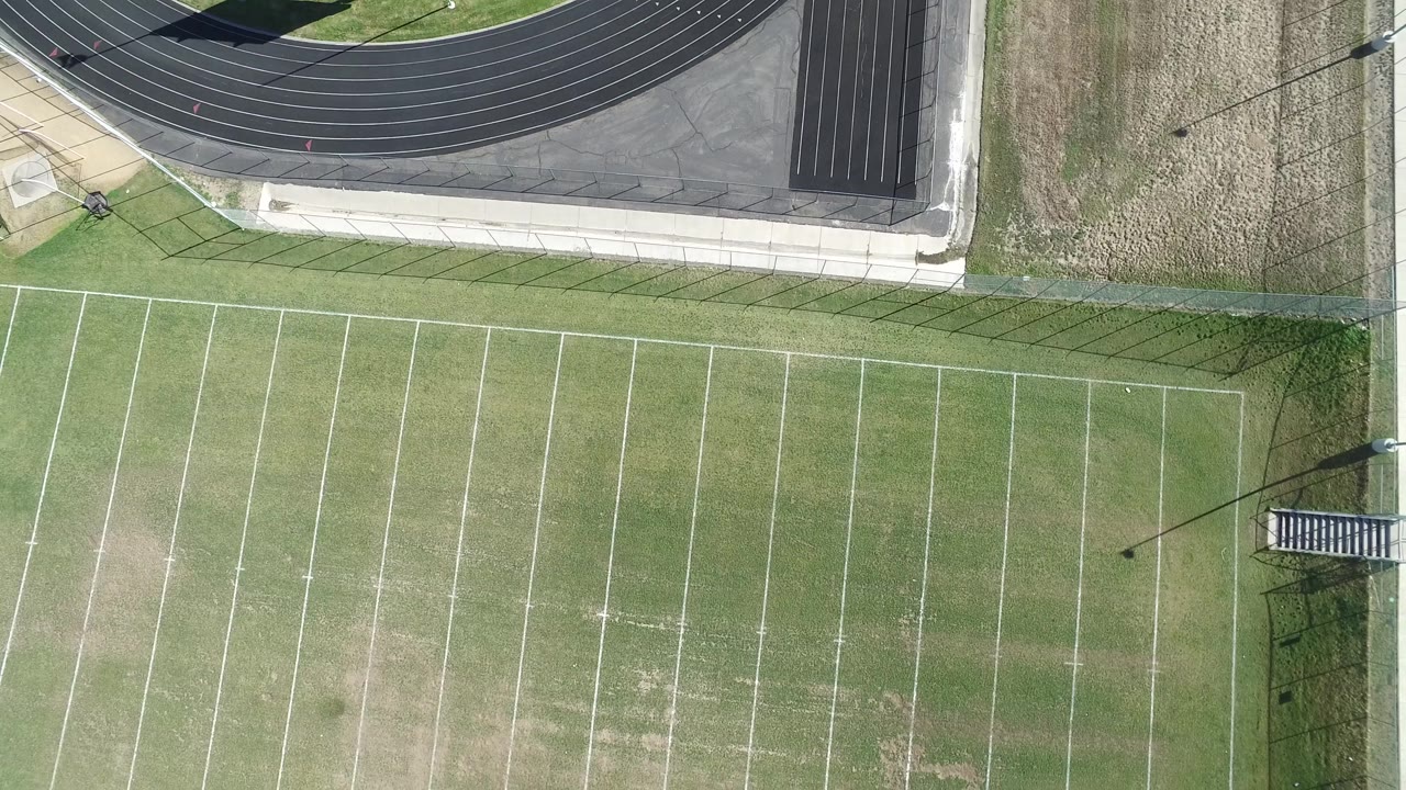 Top-down football field with track, sidewalk, and light pole