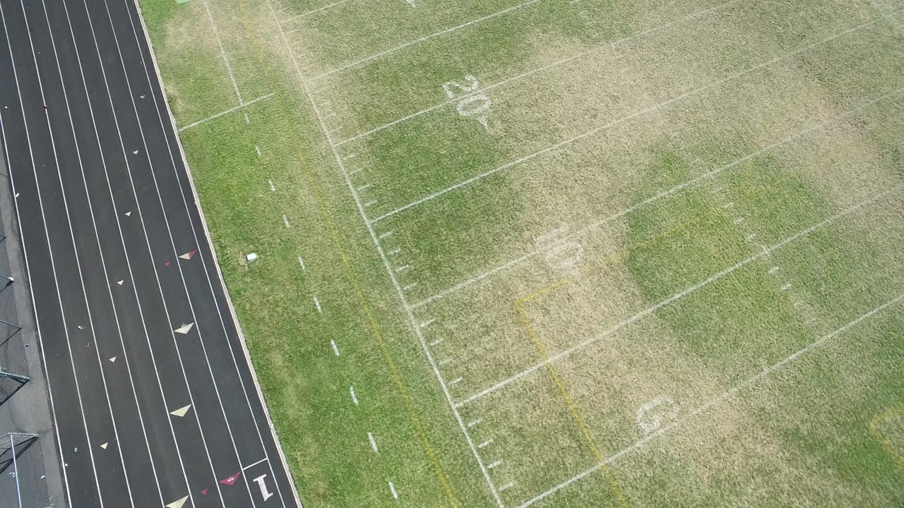 High-angle Hidden Lake, Colorado view with football field lines crossing the frame and the running track along the right edge, with no visible people.
