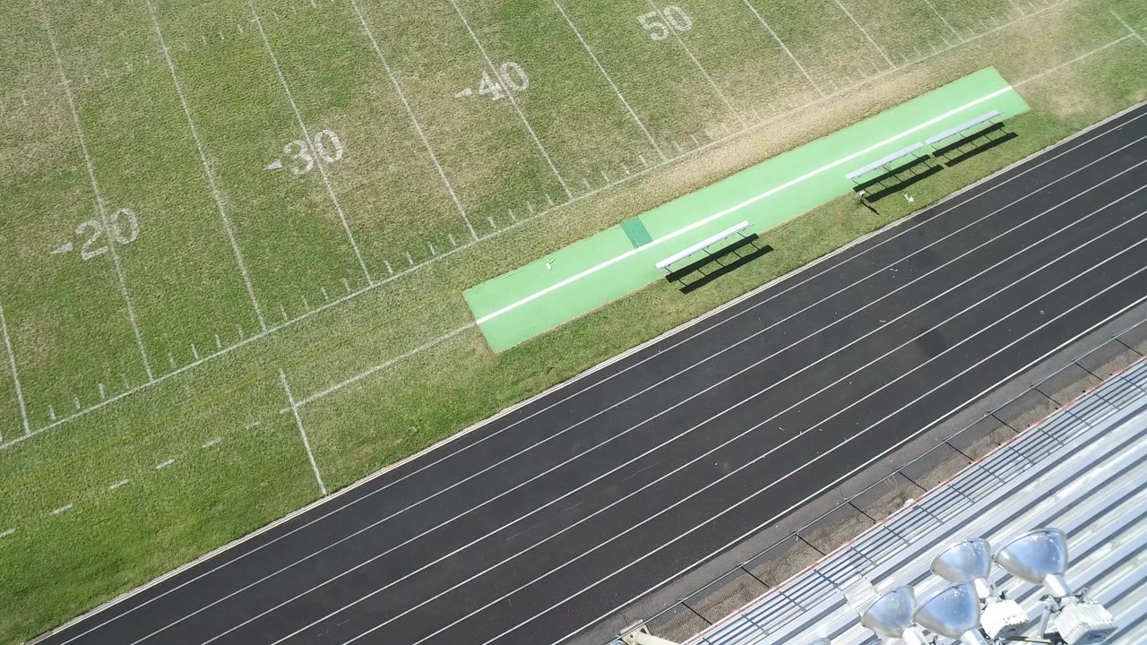 Overhead view of a football field beside a running track and bleachers