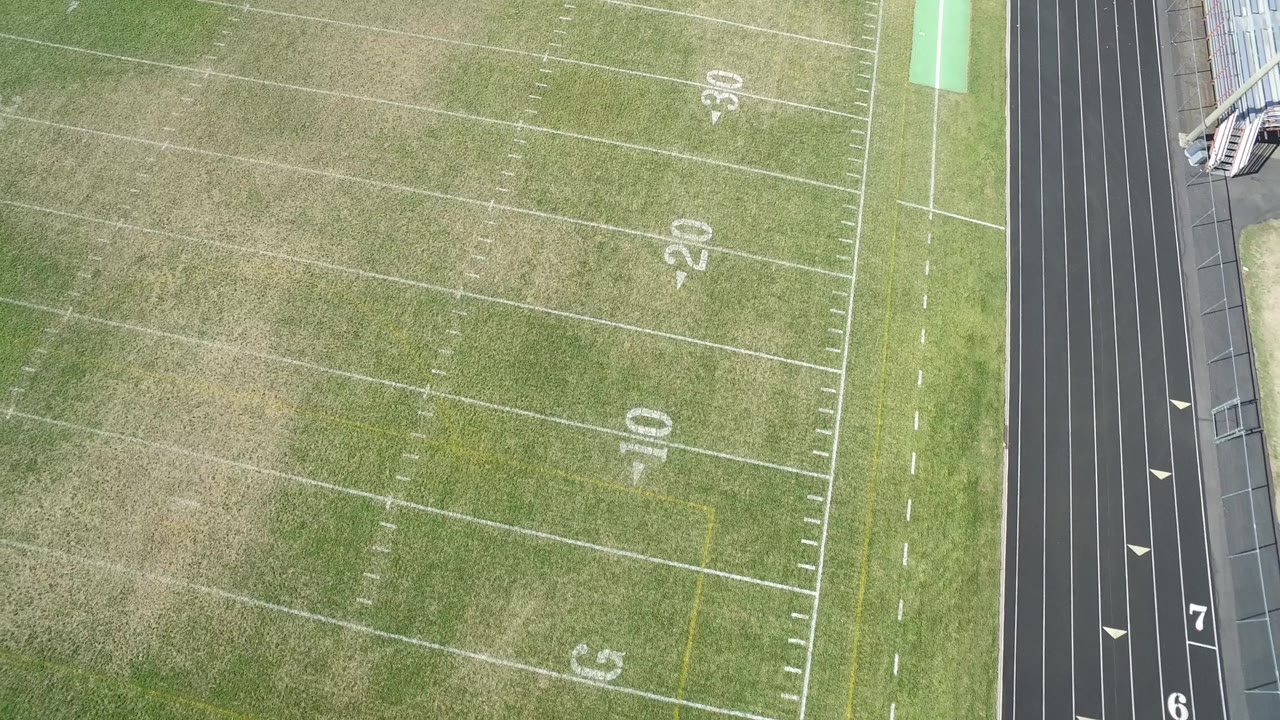 Top-down football field and track with numbered lanes visible.