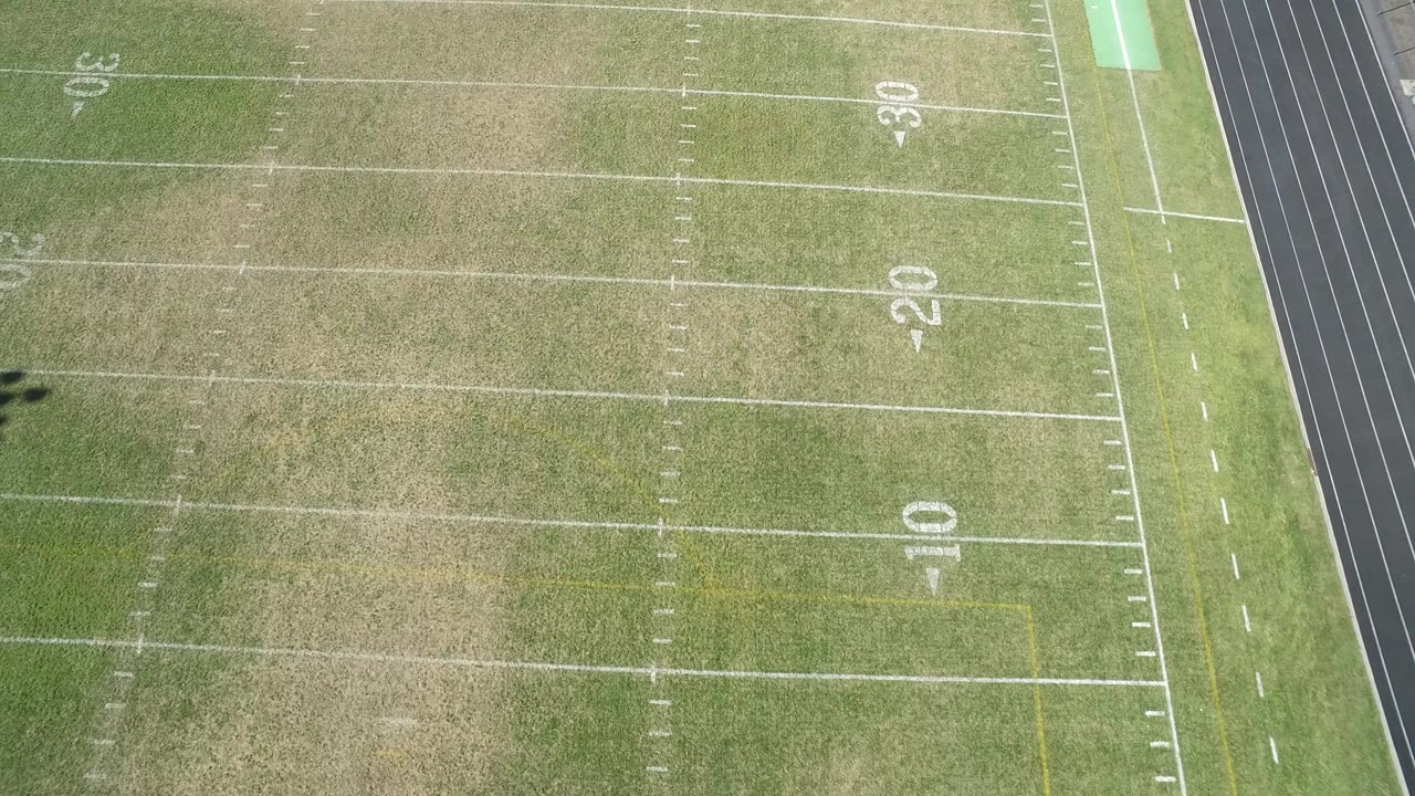 Aerial view over a marked football field in Hidden Lake, Colorado, with the 10, 20, and 30 yard numbers visible, a dark track edge at right, and no visible people.