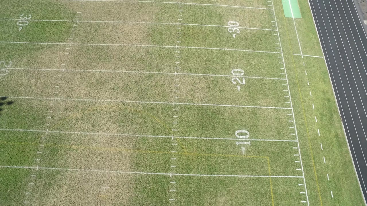 Aerial frame over the Hidden Lake, Colorado football field, showing faded turf, white yard lines, large 10, 20, and 30 numbers, a sideline strip, and no visible people.