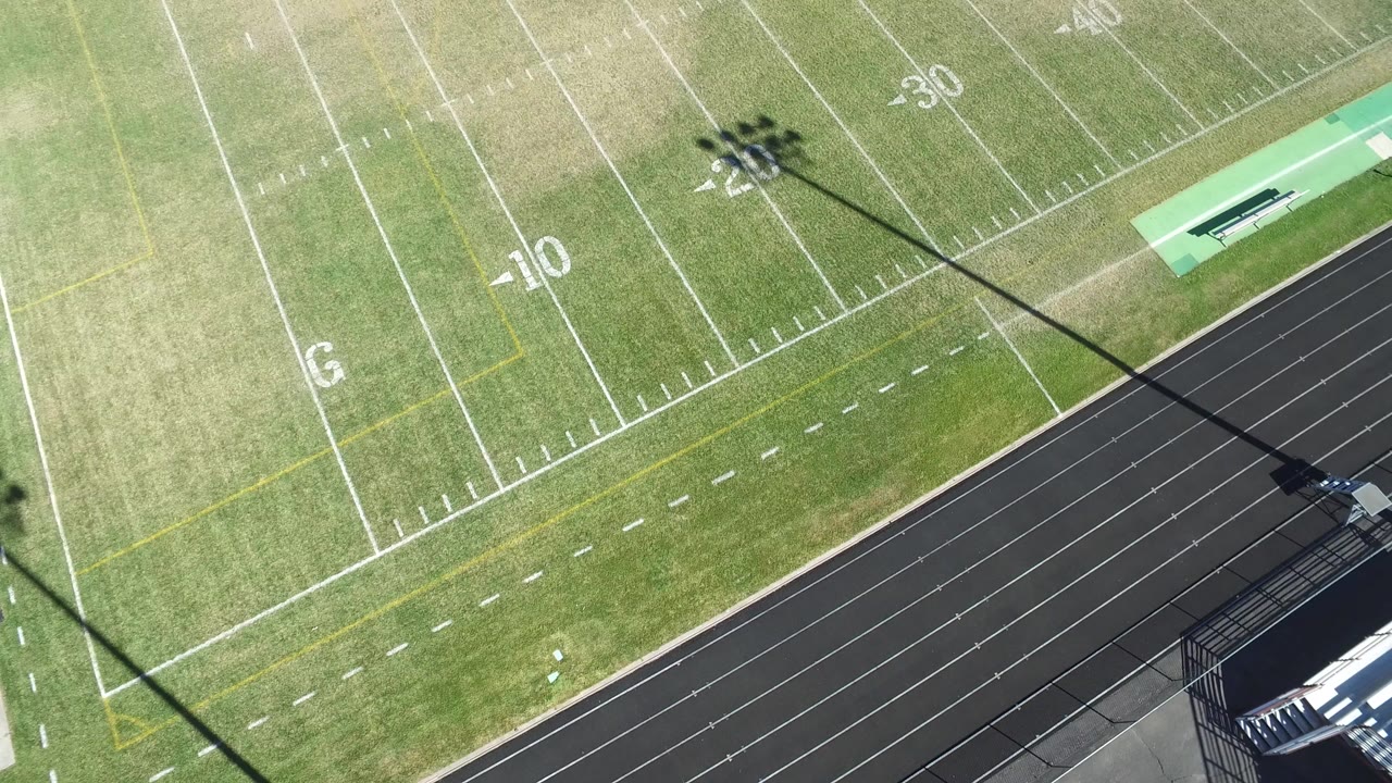 Overhead view of a green football field beside a black running track.
