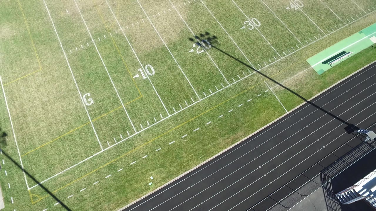Aerial frame over the Hidden Lake football field, showing the 10 and 30 yard markings, turf color variation, the track edge, and no visible people.