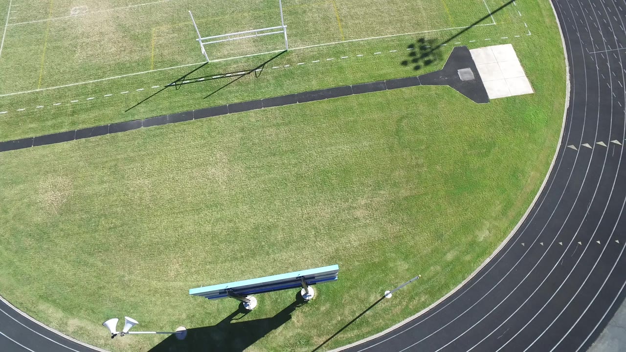 Aerial frame in Hidden Lake, Colorado with the black running track curving along the right, open green field at center, a soccer goal near the top, and no visible people.