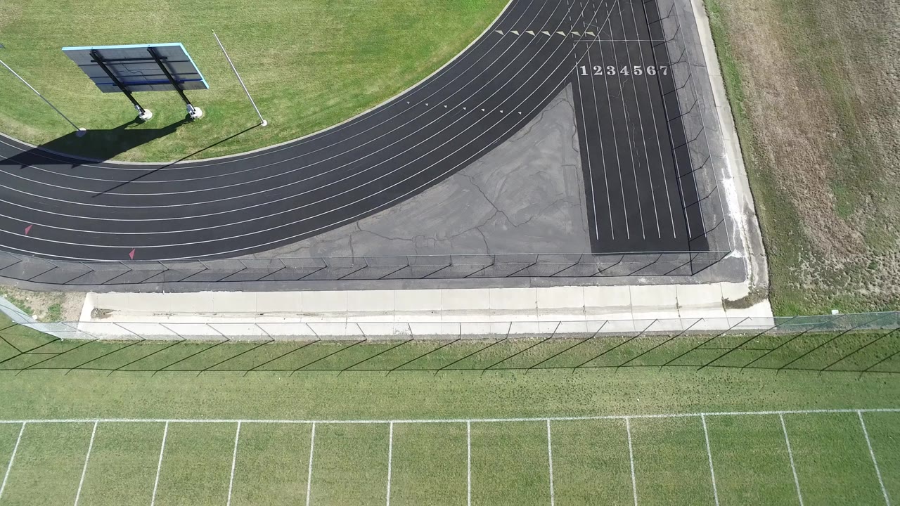 A second overhead view in Hidden Lake, Colorado holds on the track curve, numbered lanes, pale walkway, surrounding grass, and no visible people.