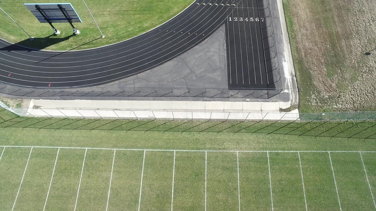 Top-down view of track lanes and football field stripes.