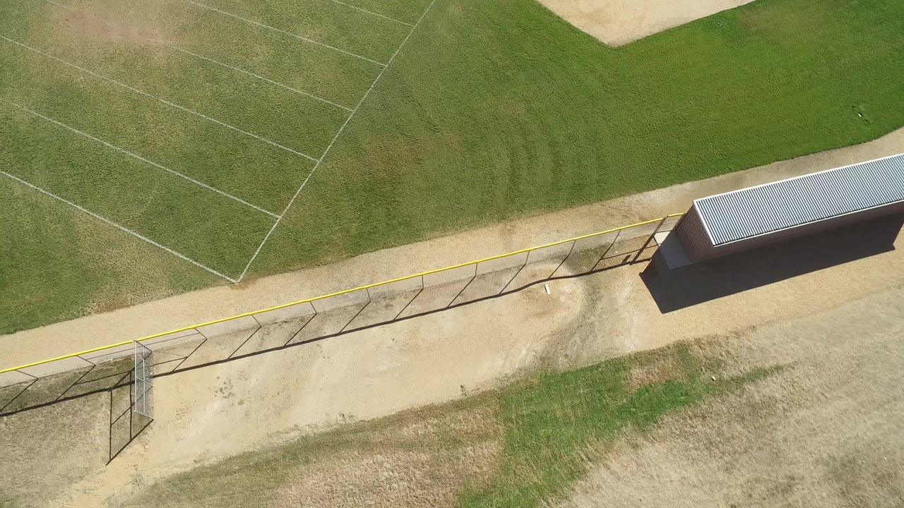 Aerial view in Hidden Lake, Colorado with the fence and yellow top edge crossing the lower frame, a roofed structure near the path, marked grass, and no visible people.