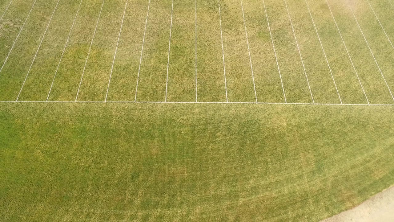 High overhead frame in Hidden Lake, Colorado, showing a broad green turf band below pale field markings, with no visible people.