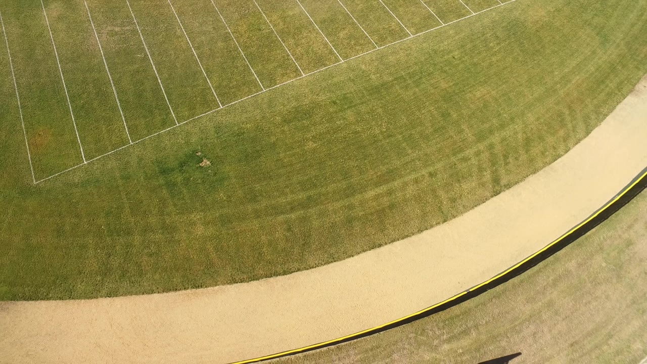 Green field from above with a broad pale curve and painted markings.