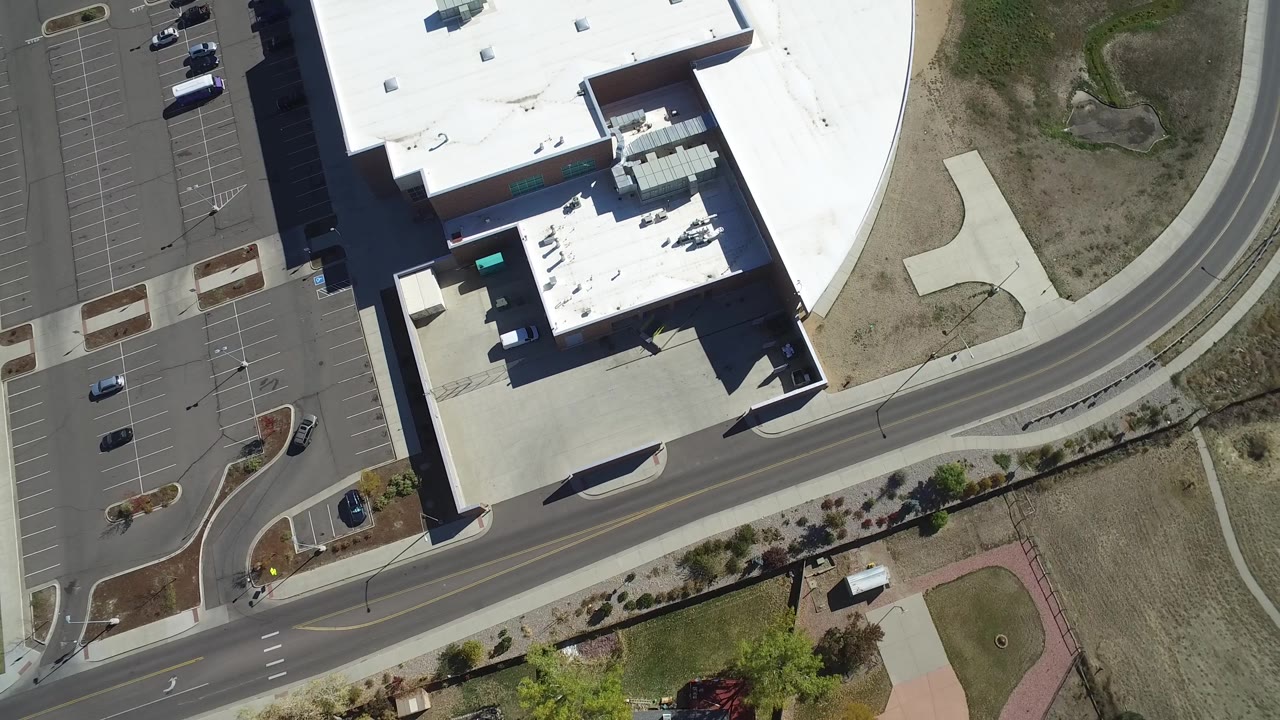 Top-down view of a large building, adjacent road, and dry open terrain