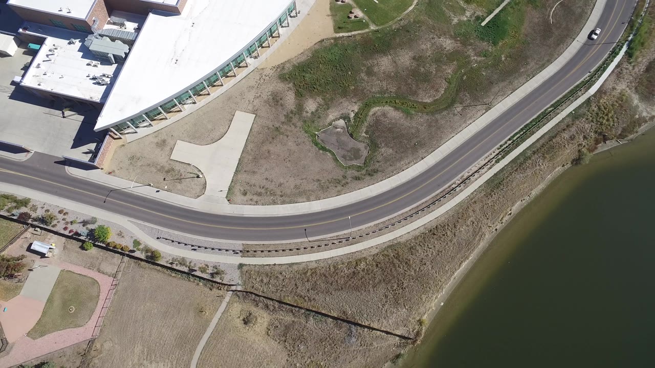 Top-down road and lake edge with a small car on the road.
