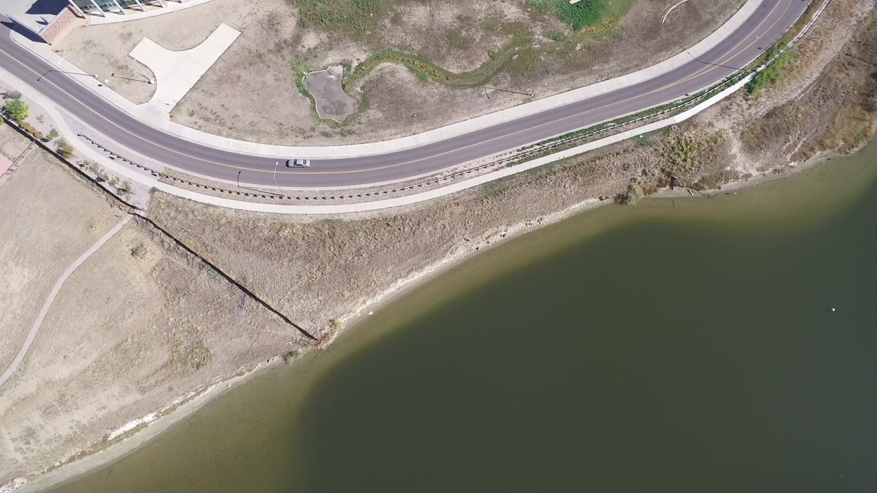 Curved road and lake edge with a car near the upper frame