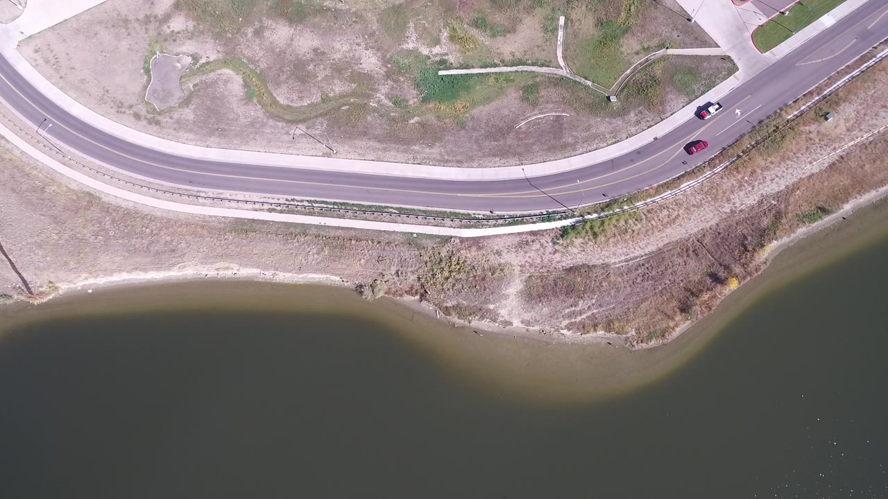 Overhead view of a curved road beside a lake shoreline