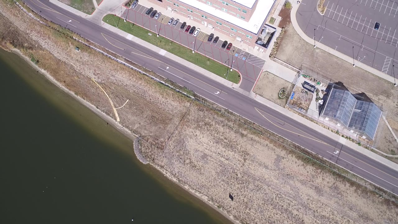 Top-down shoreline with road and mostly empty parking lot