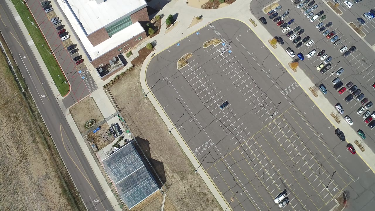 Top-down mall parking lot with road and sidewalks along the edges.