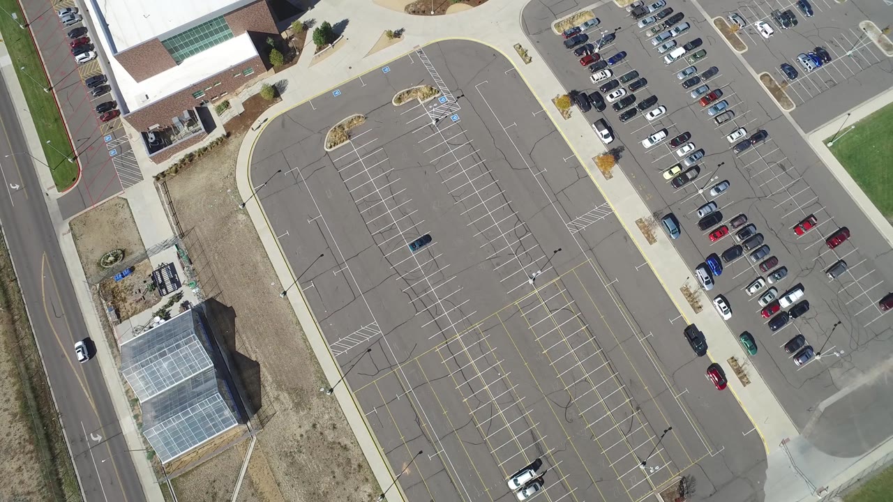 Top-down parking lot with road, cars, and landscaped edges