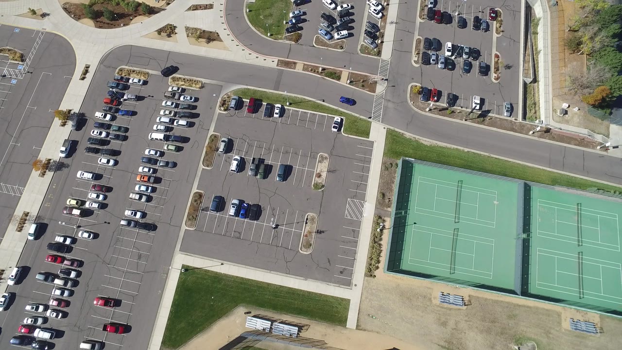 Top-down parking area with tennis courts and surrounding streets.