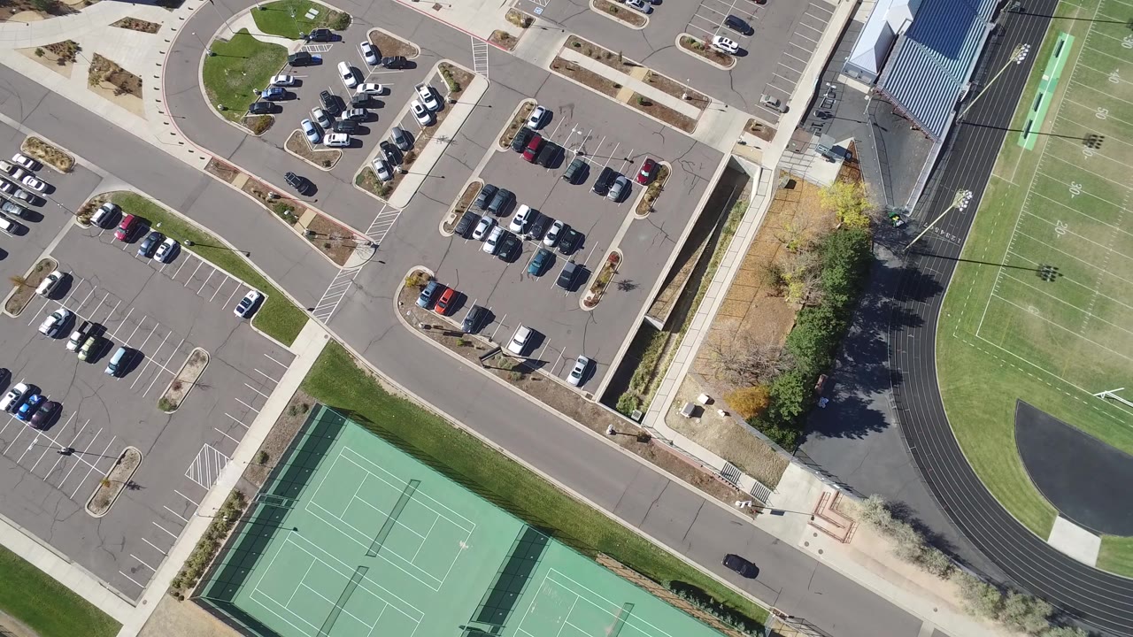 Overhead view of parking lots, roads, tennis courts, track, and sports field.