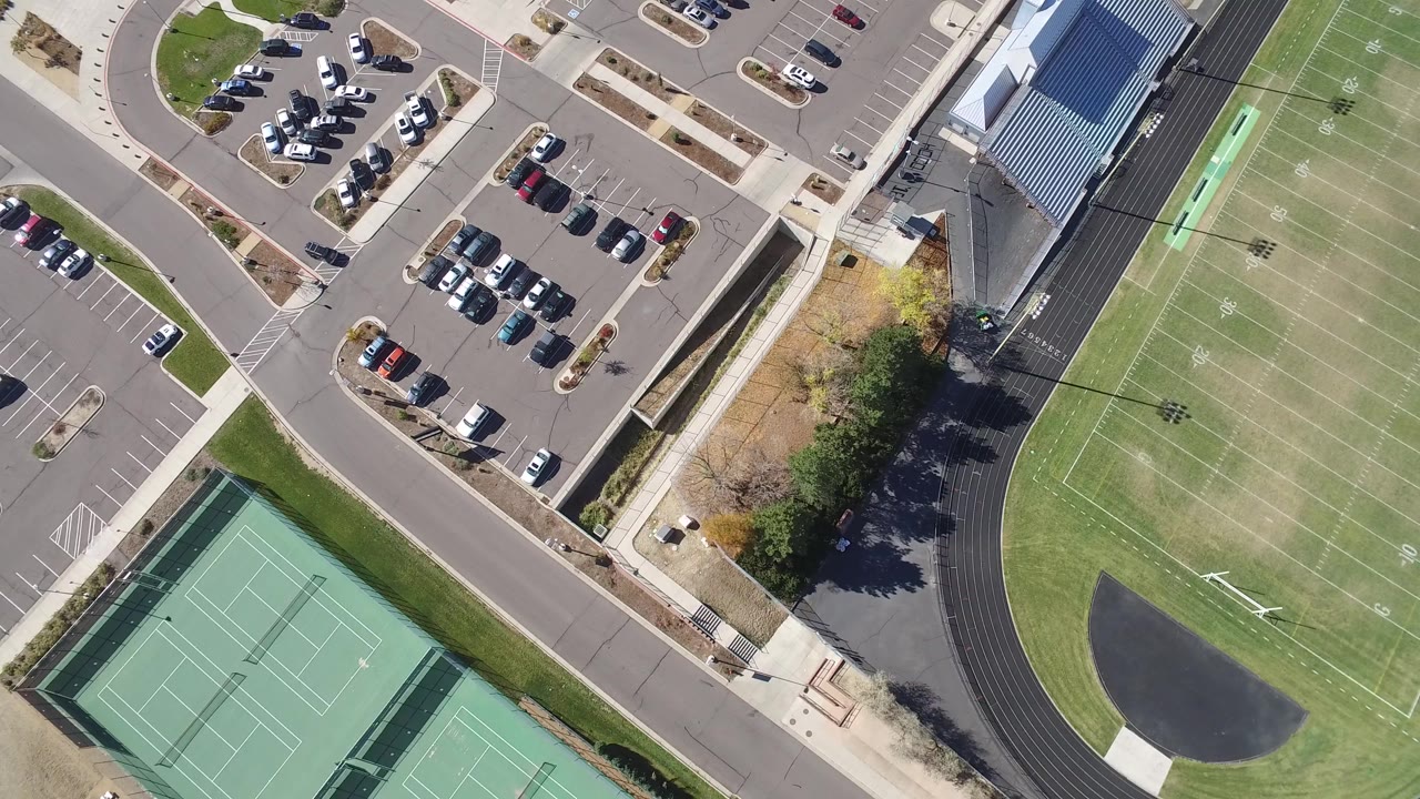 Overhead view of tennis courts, parking lots, road, football field, and track.
