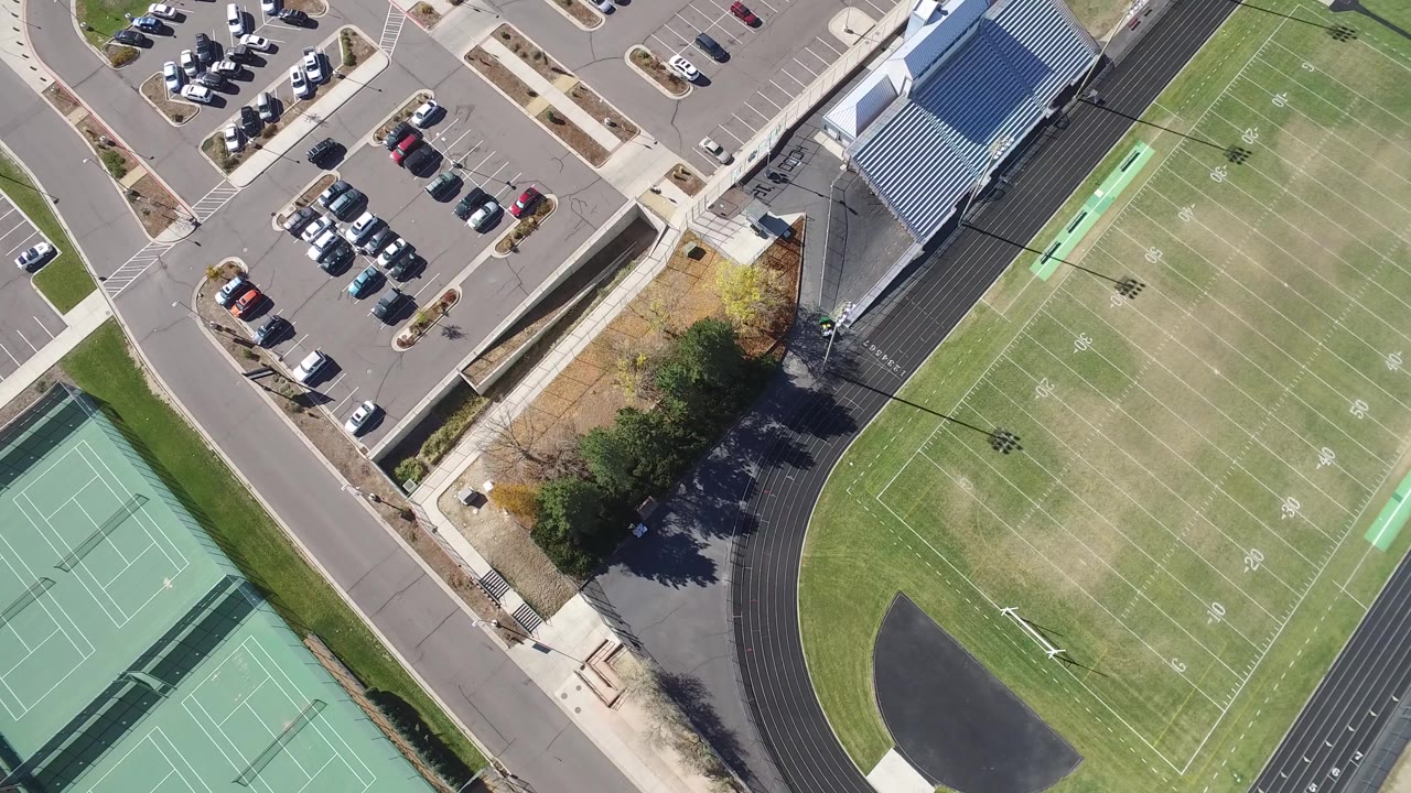 Overhead view of parking lot, athletic field, track, and tennis courts.